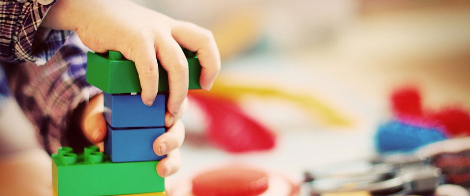 a child playing with large, colored, plastic, building bricks